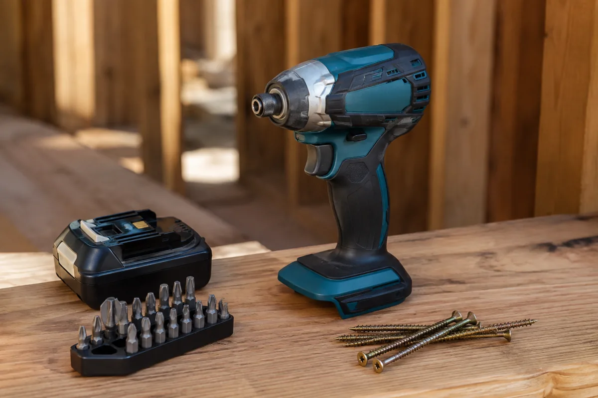 Editorial illustration: cordless impact driver beside driver bits and screws.